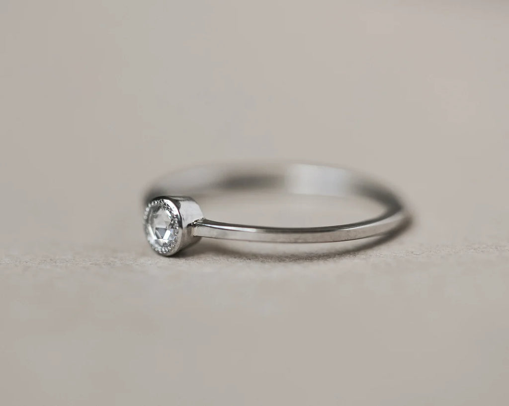 Silver ring with a diamond on a light gray background