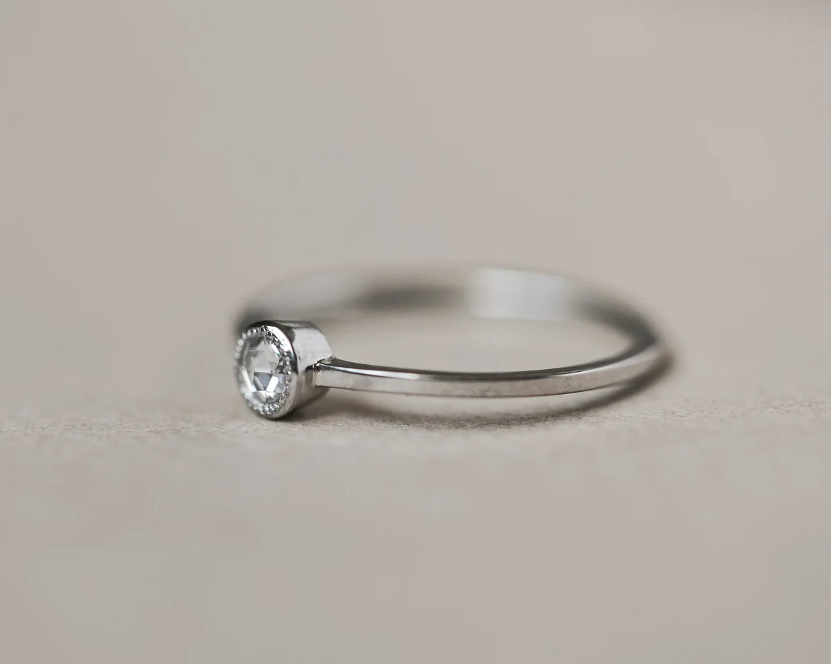 Silver ring with a diamond on a light gray background