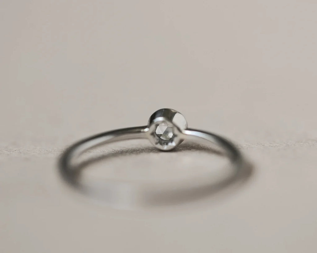 Silver ring with a small gemstone on a light gray background