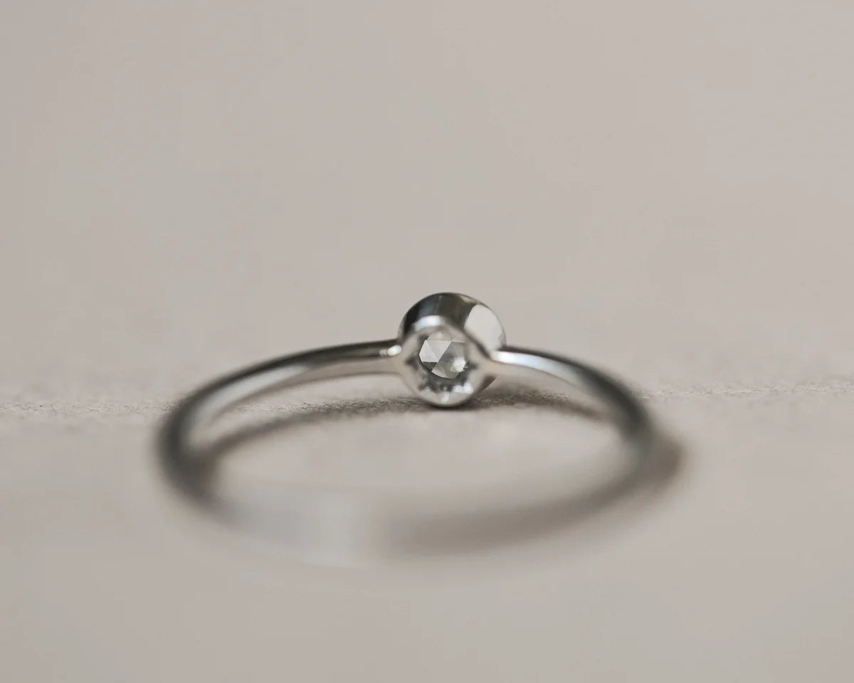 Silver ring with a small gemstone on a light gray background