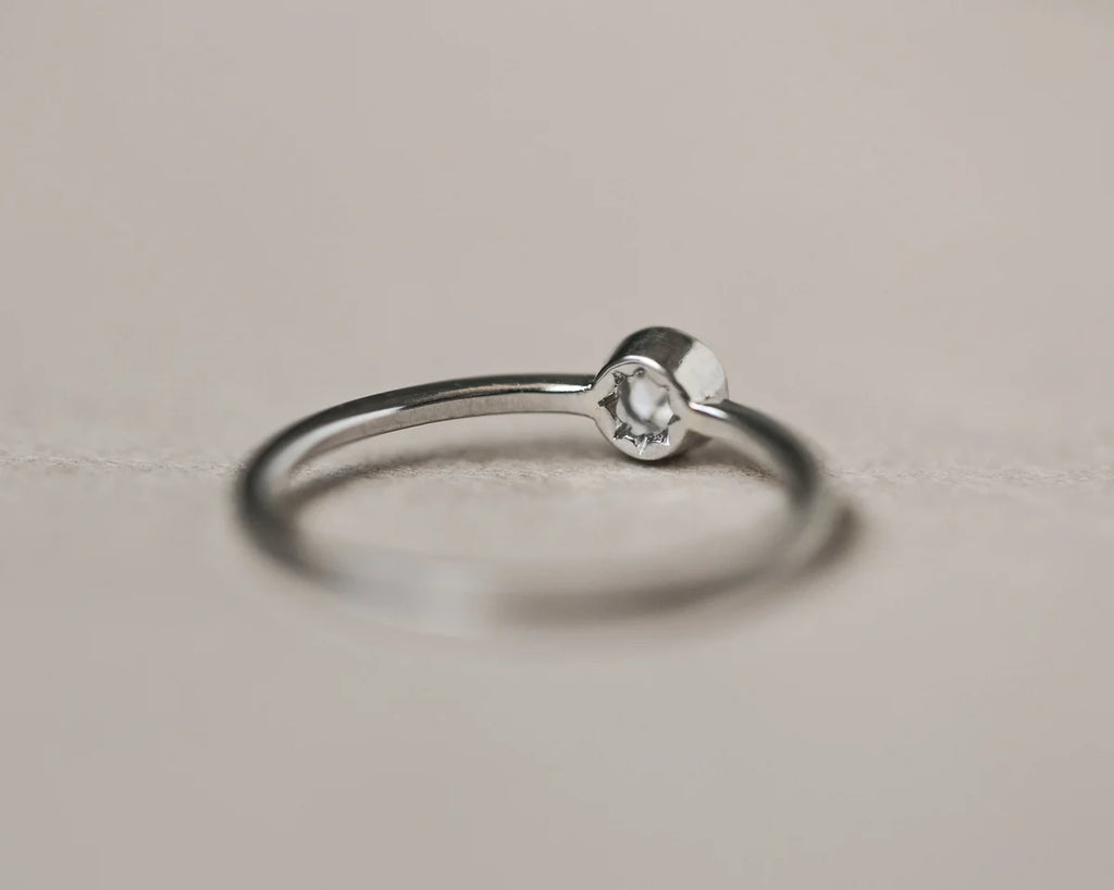 Silver ring with a small diamond on a light gray background