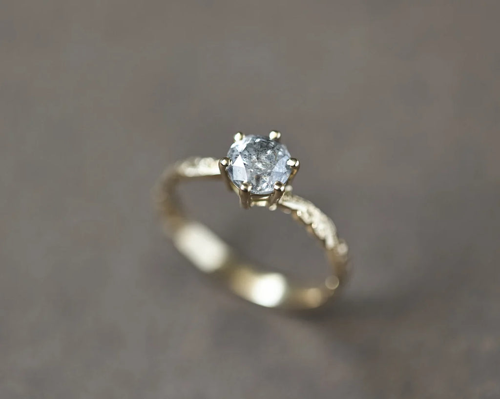 Soft focus view of 18ct yellow gold grey diamond engagement ring