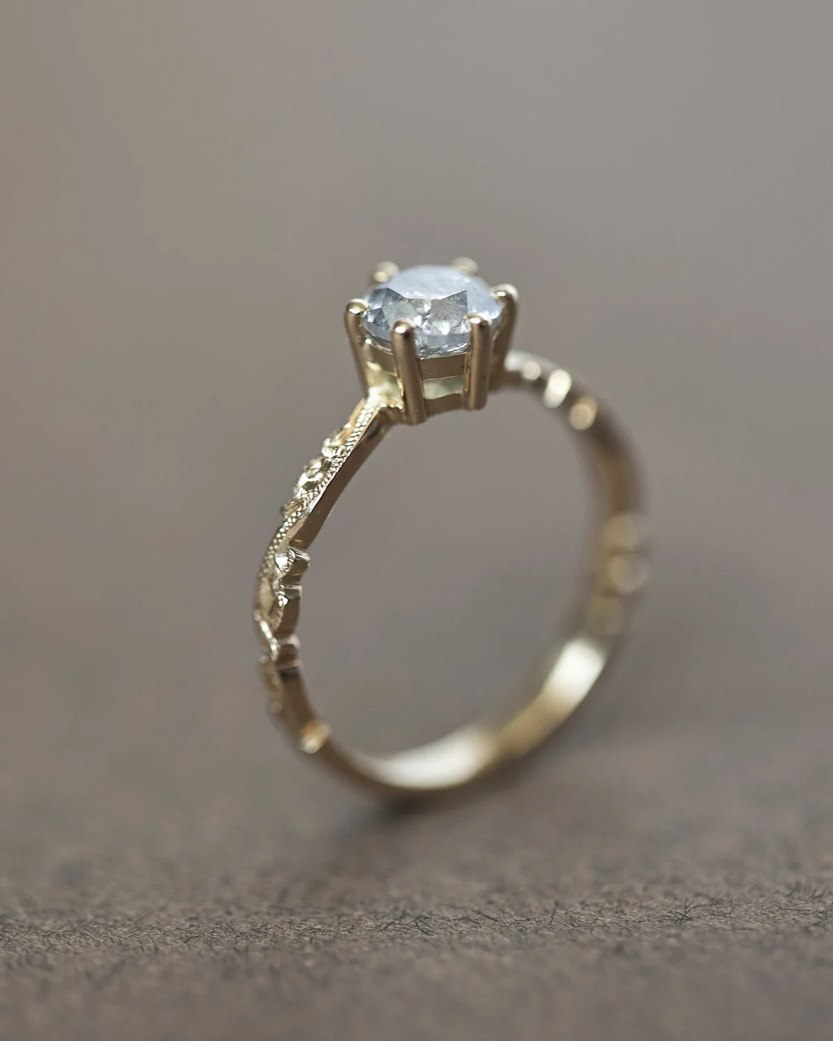 Side view of grey brilliant-cut diamond ring with floral carved band