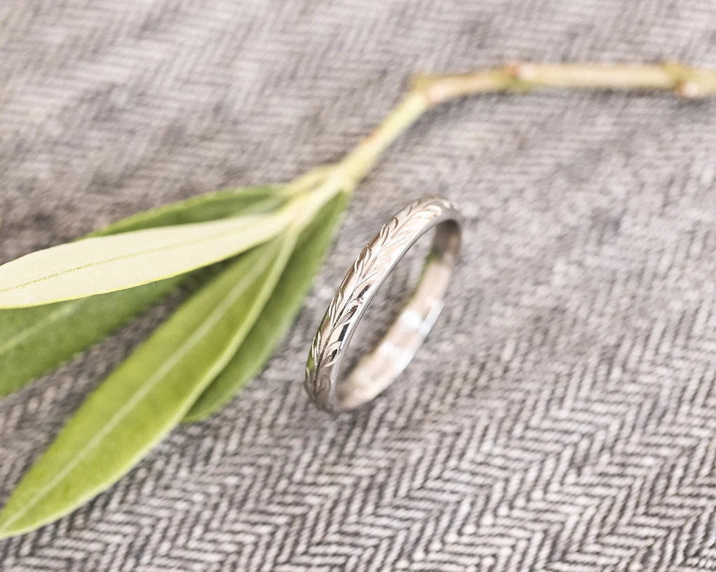 Side view of platinum olive leaf engraved wedding ring with olive branch