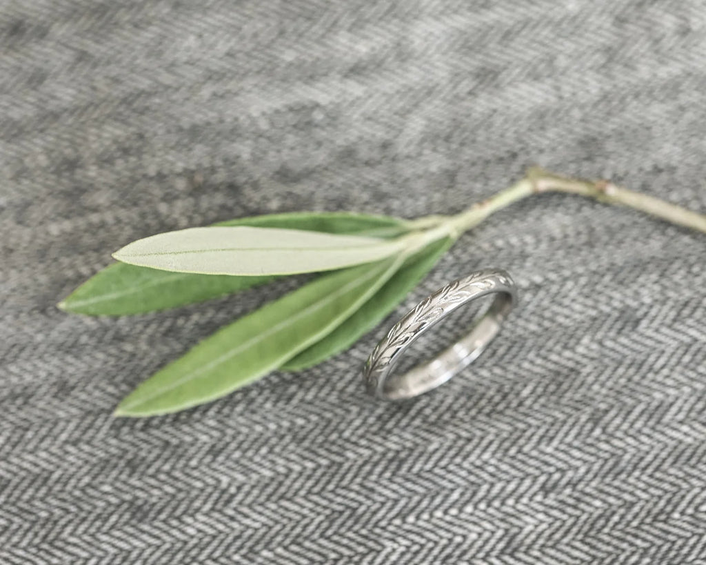 close up olive leaf engraving on platinum ring 3mm band texture