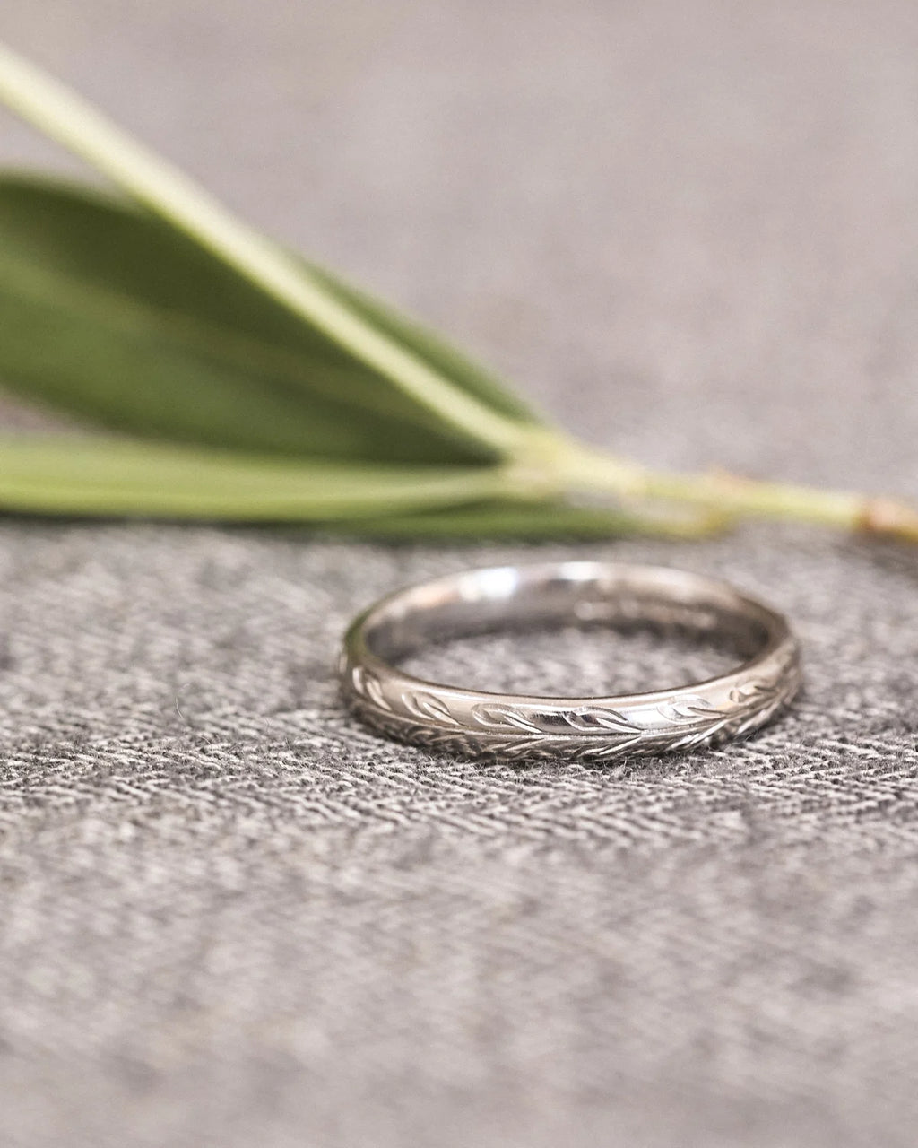 Close-up of platinum wedding ring with olive leaf engraving