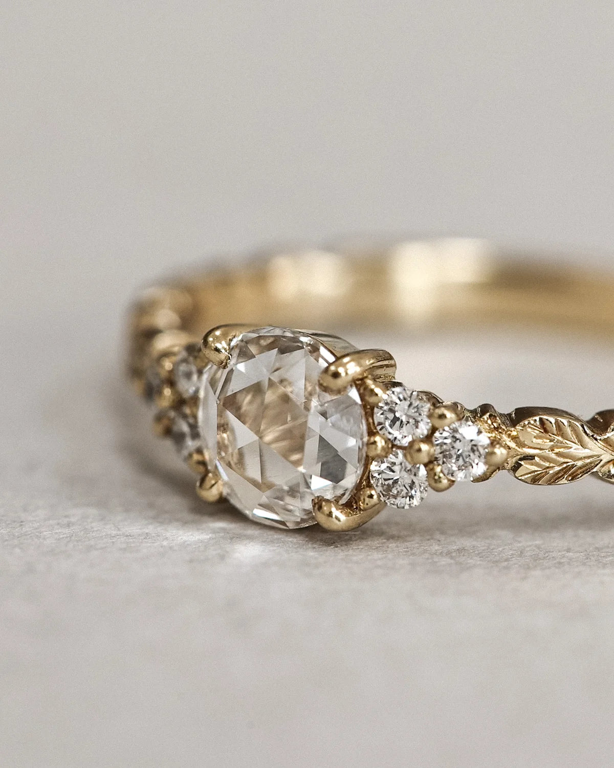 Close-up of 18ct yellow gold laurel leaf ring with rose-cut diamond