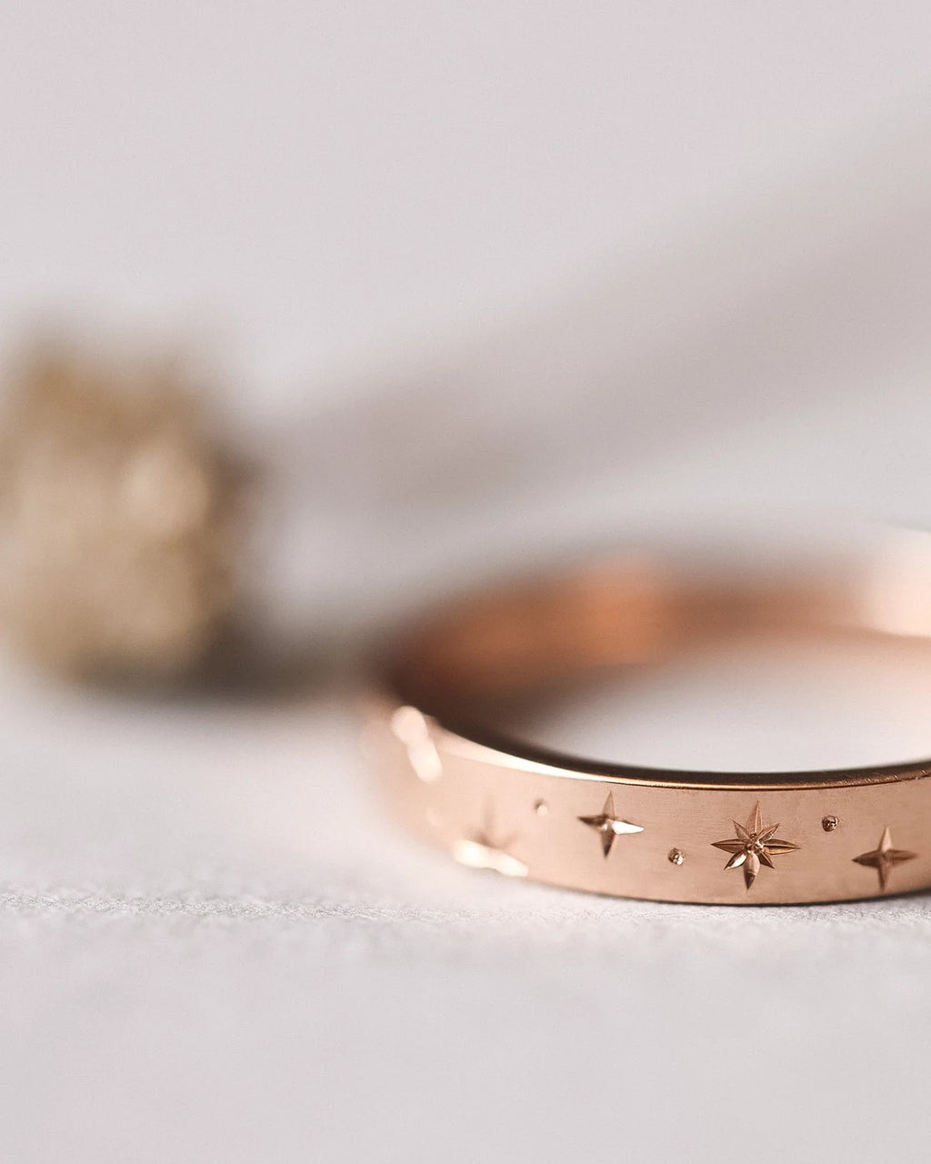 Soft focus view of champagne diamond star setting on rose gold band