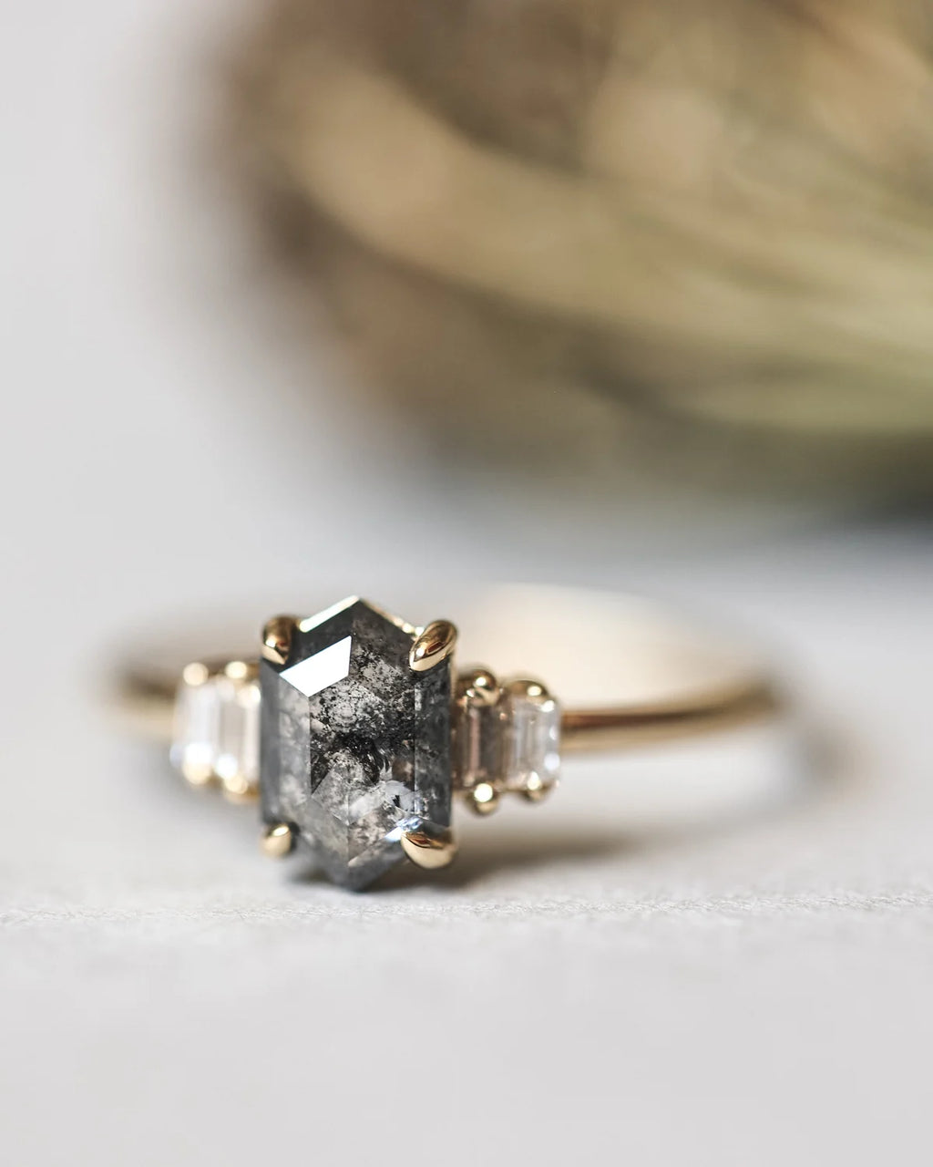 Front view of dark grey hexagonal diamond ring with champagne baguette diamonds