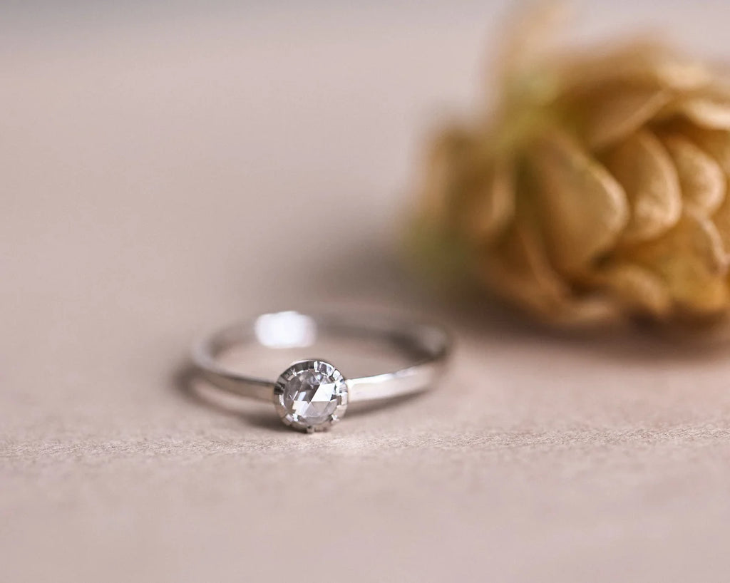 Close-up of platinum rose-cut diamond ring styled with dried flower