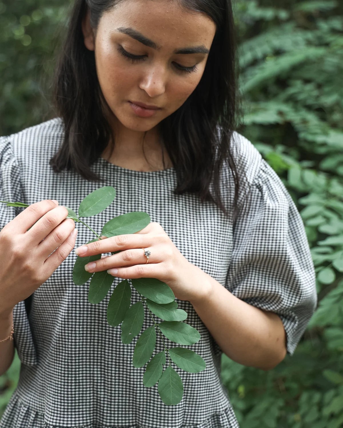 Lifestyle image of dark grey diamond ring worn with botanical styling