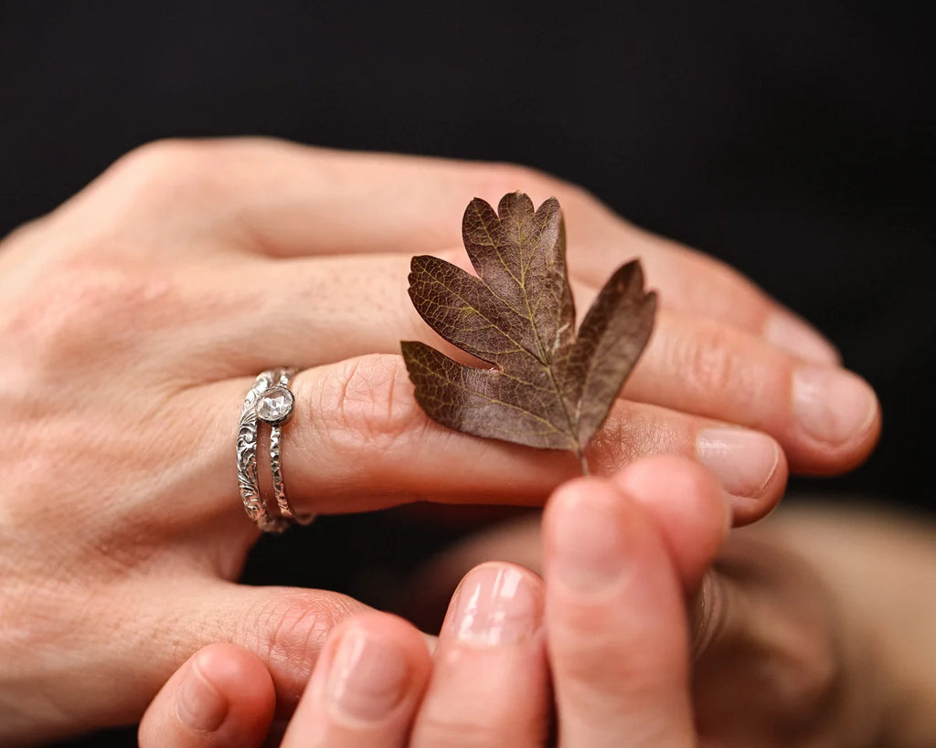 Platinum rose-cut diamond ring worn on hand with autumn leaf