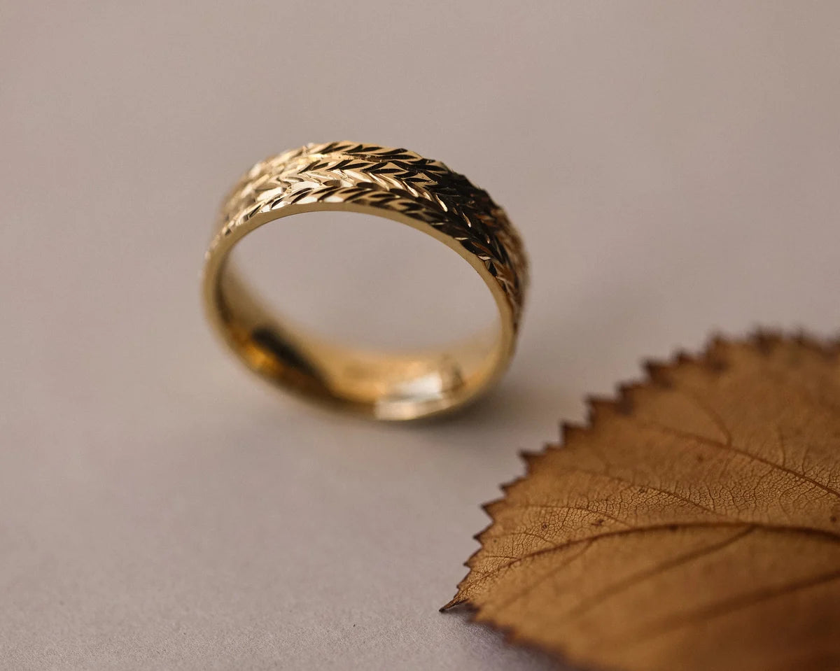 Angled view of 18ct yellow gold herringbone engraved wedding ring