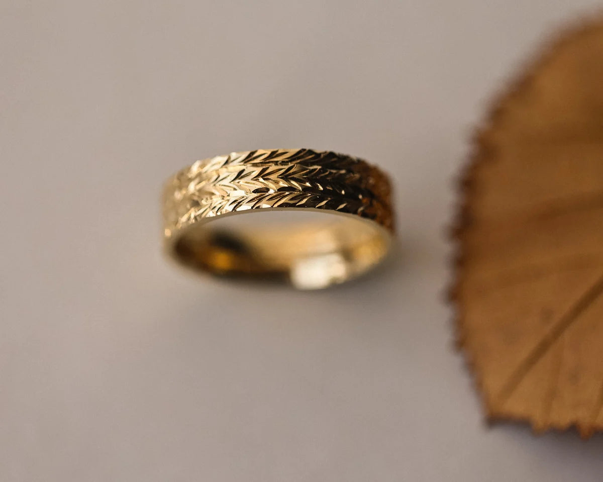 Front view of 6mm herringbone wedding band in yellow gold