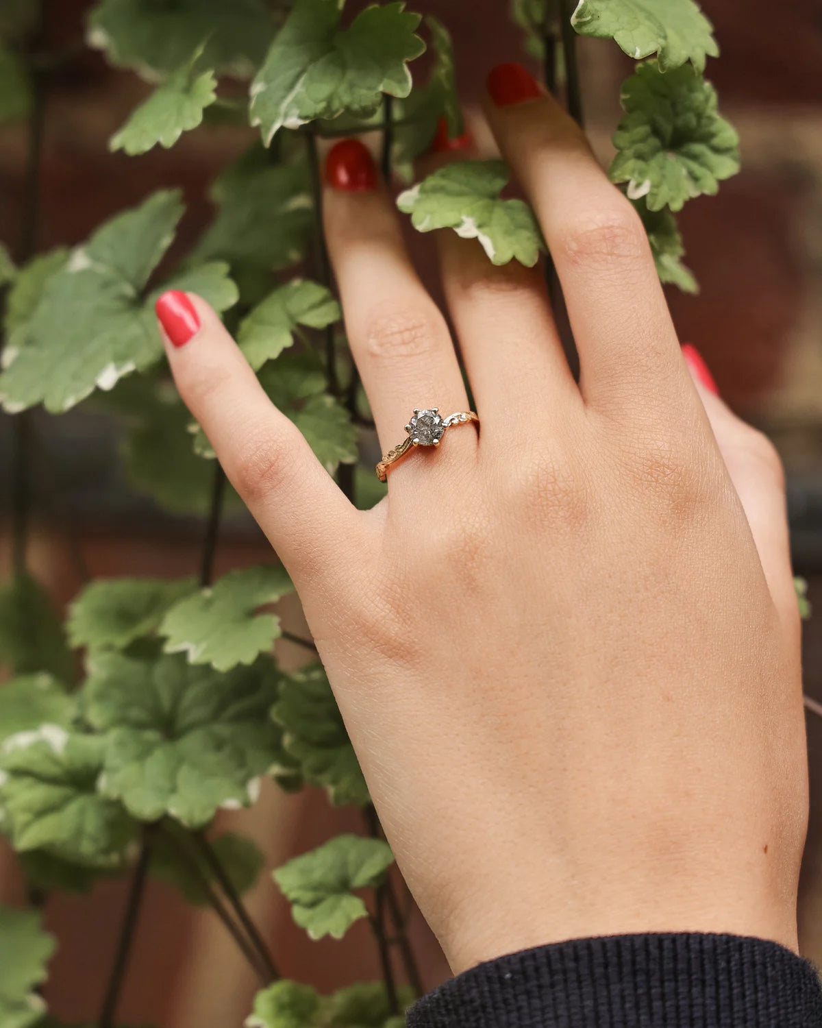 Grey salt and pepper diamond ring worn on hand with red nails