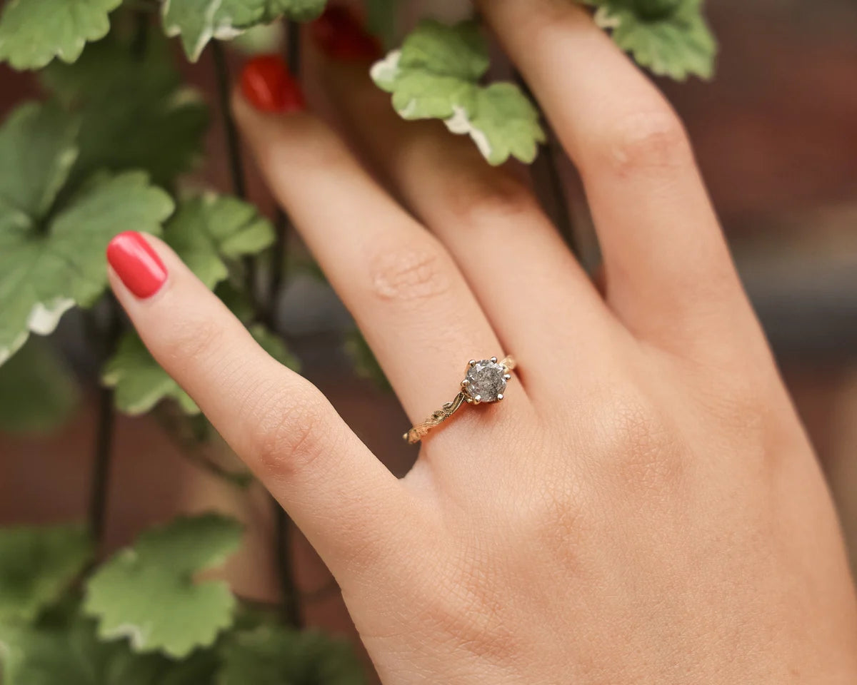 Grey salt and pepper diamond ring worn on hand with green leaves
