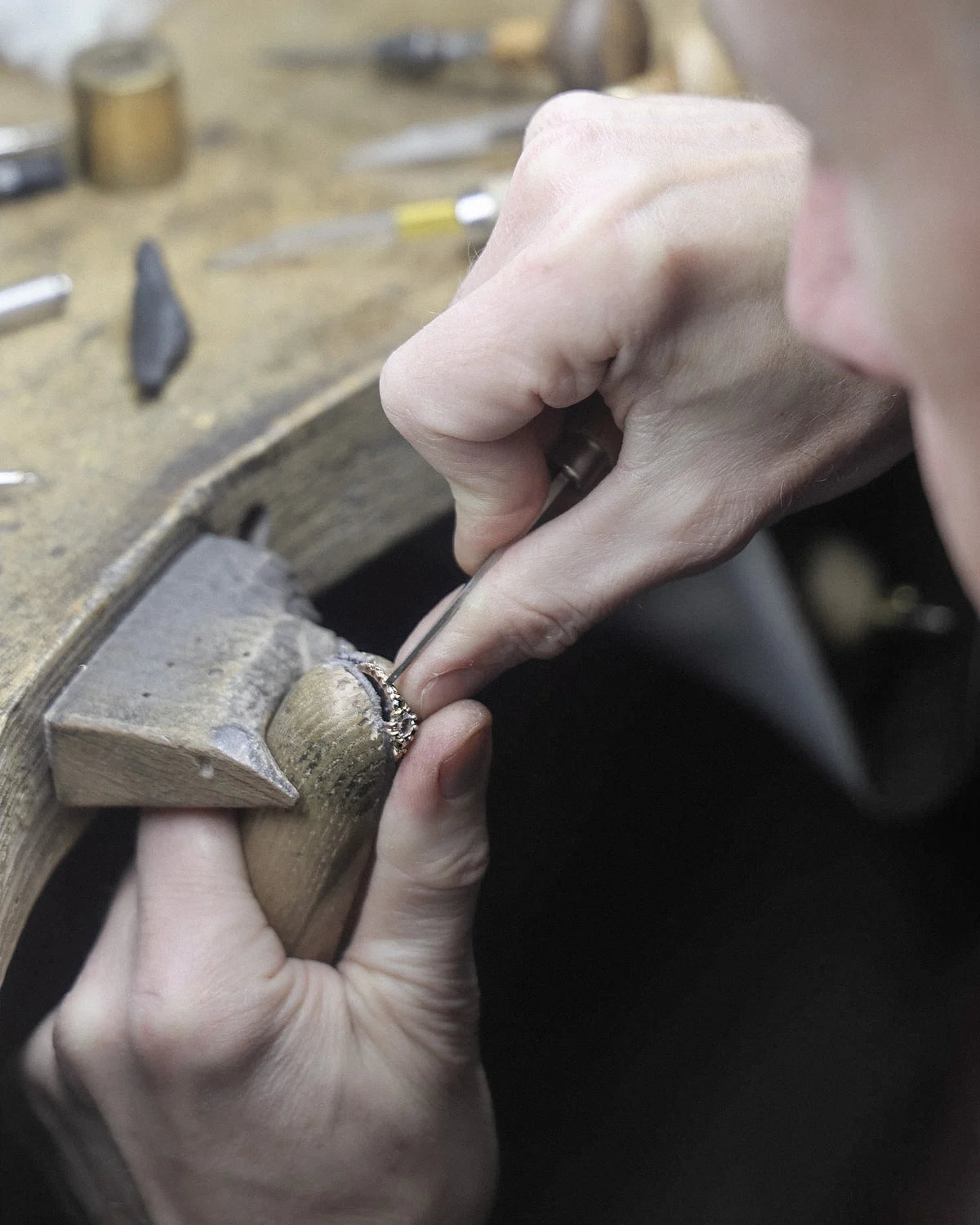 Close-up of hands working on a small object with tools in the background