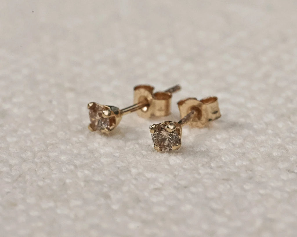 Pair of gold stud earrings on a light gray background