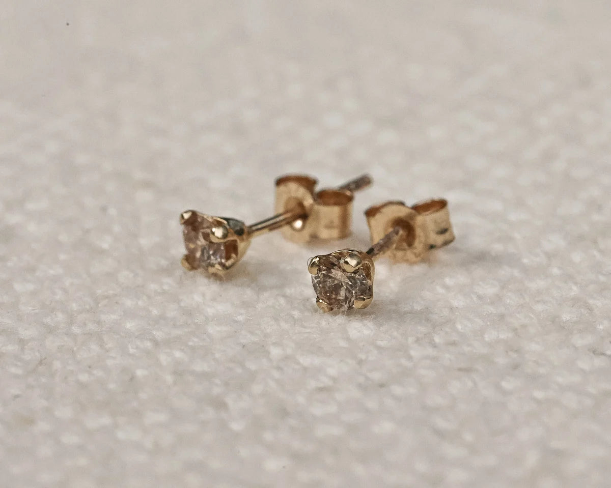 Pair of gold stud earrings on a light gray background