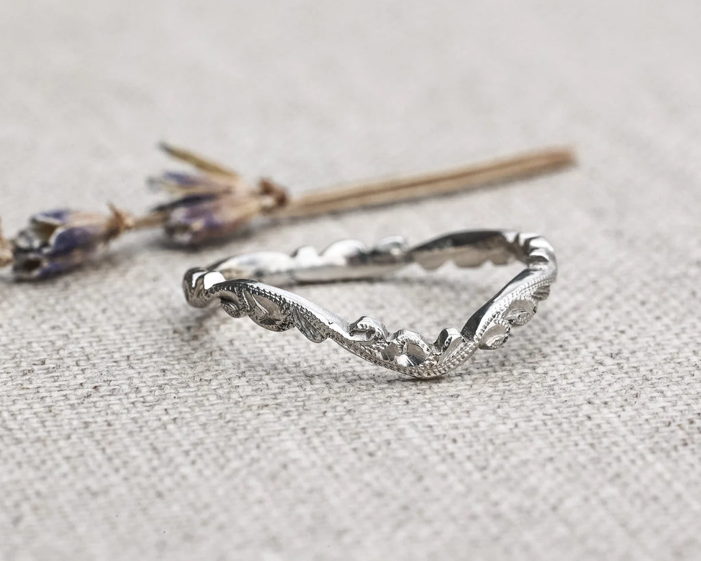 Silver ring with wavy design on a textured gray surface