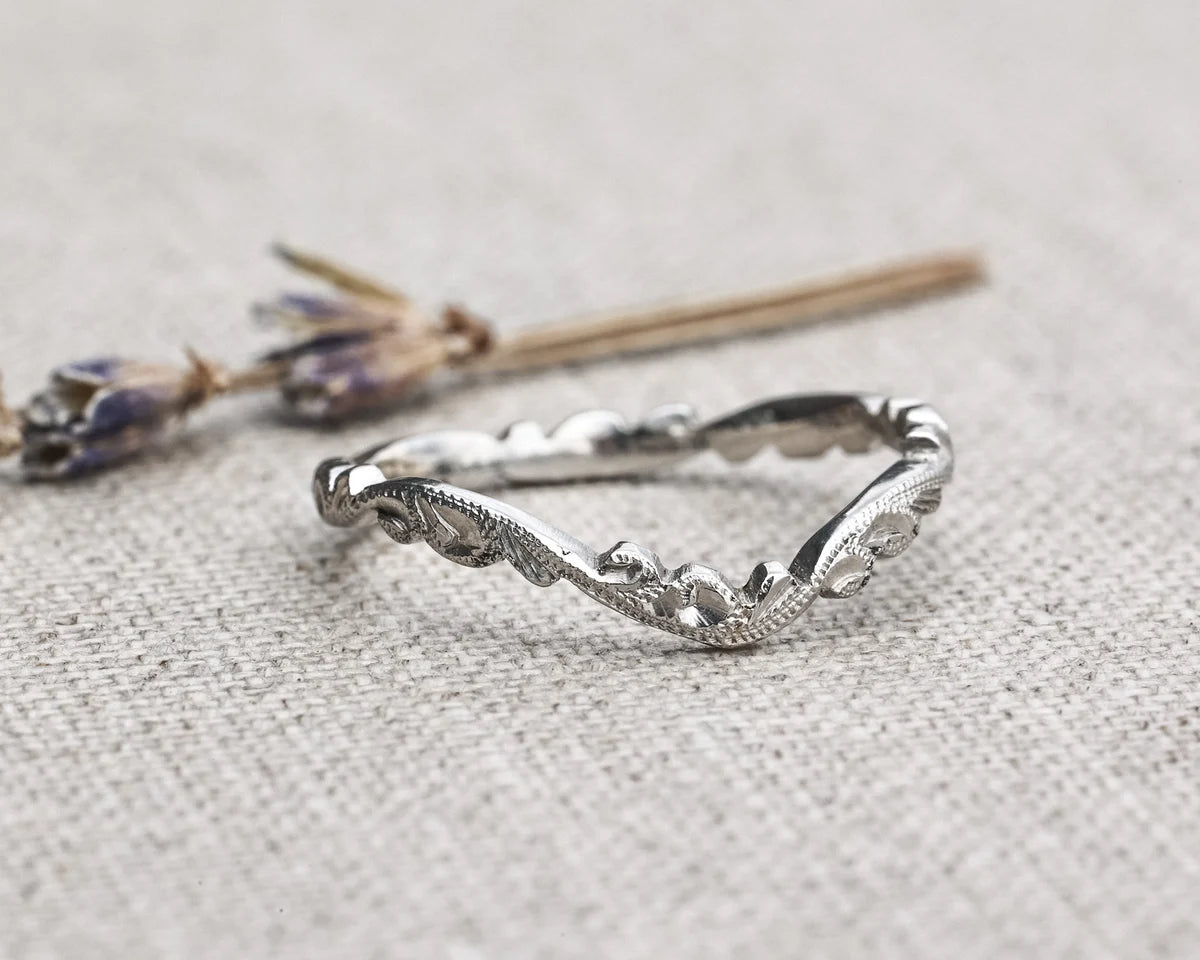 Silver ring with wavy design on a textured gray surface