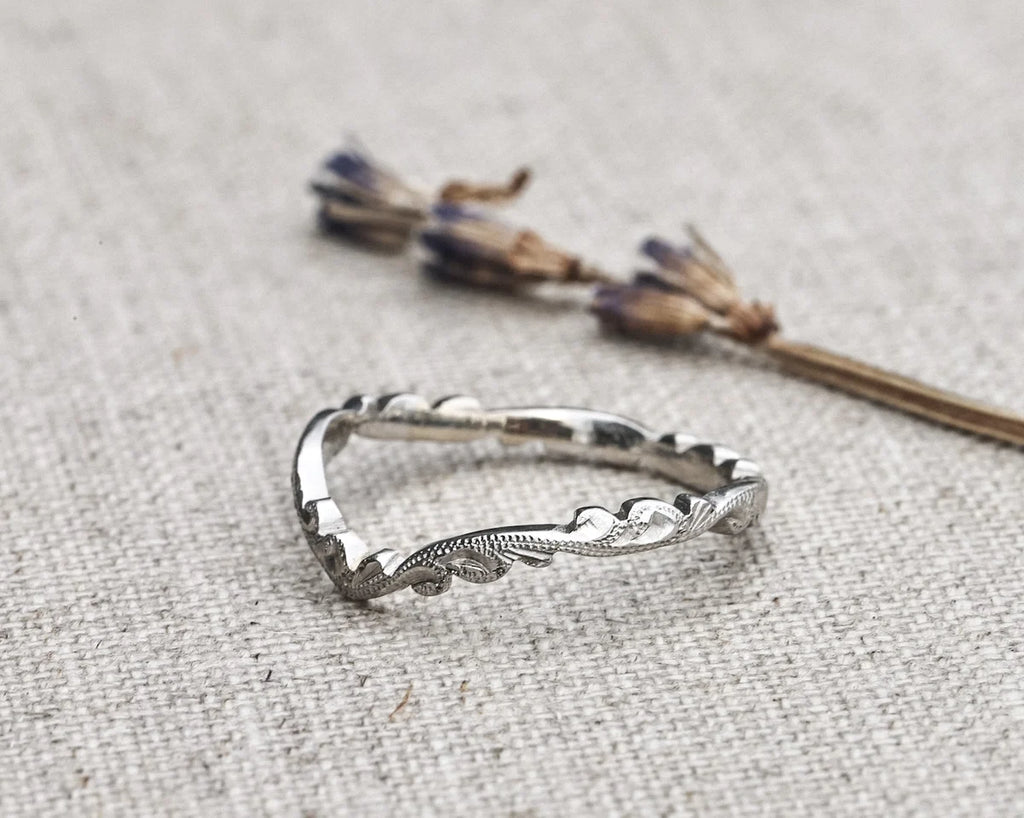 Silver ring with leaf design on a textured fabric background