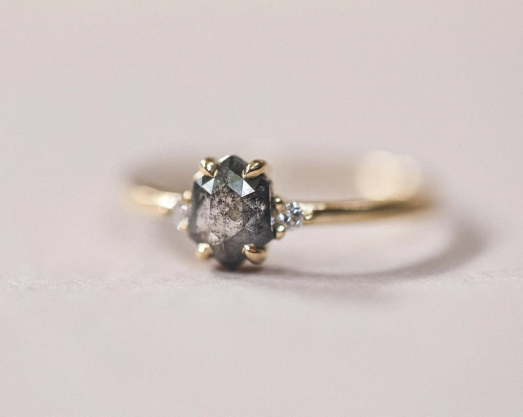 Angled view of handmade yellow gold trilogy ring with grey diamond