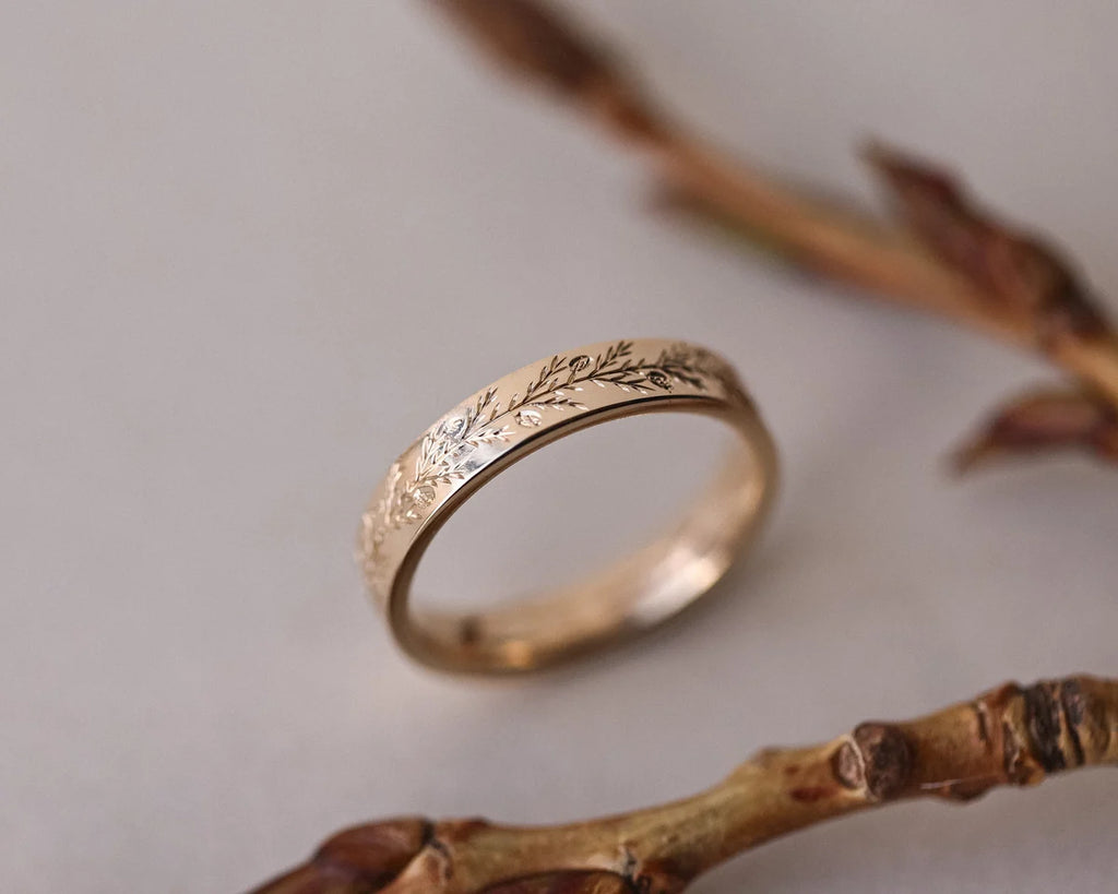 Angled view of 4mm yellow gold fir engraved wedding band