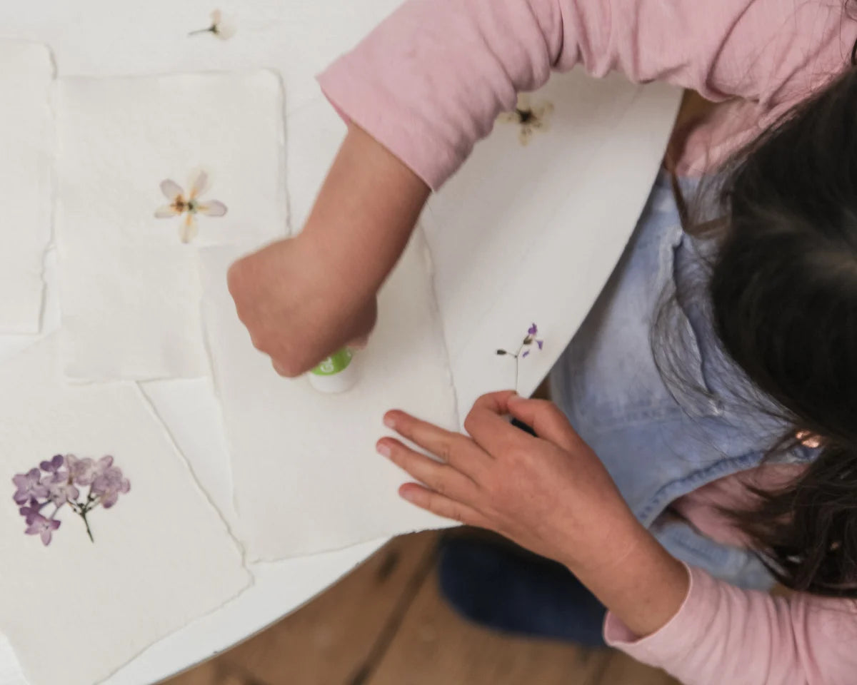 Pressed flower design process image with hand and petals