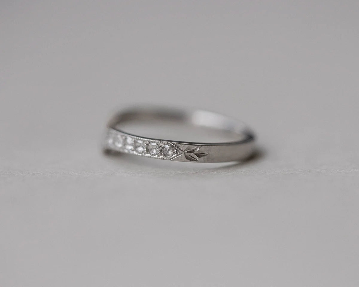 Silver ring with small diamonds on a light gray background