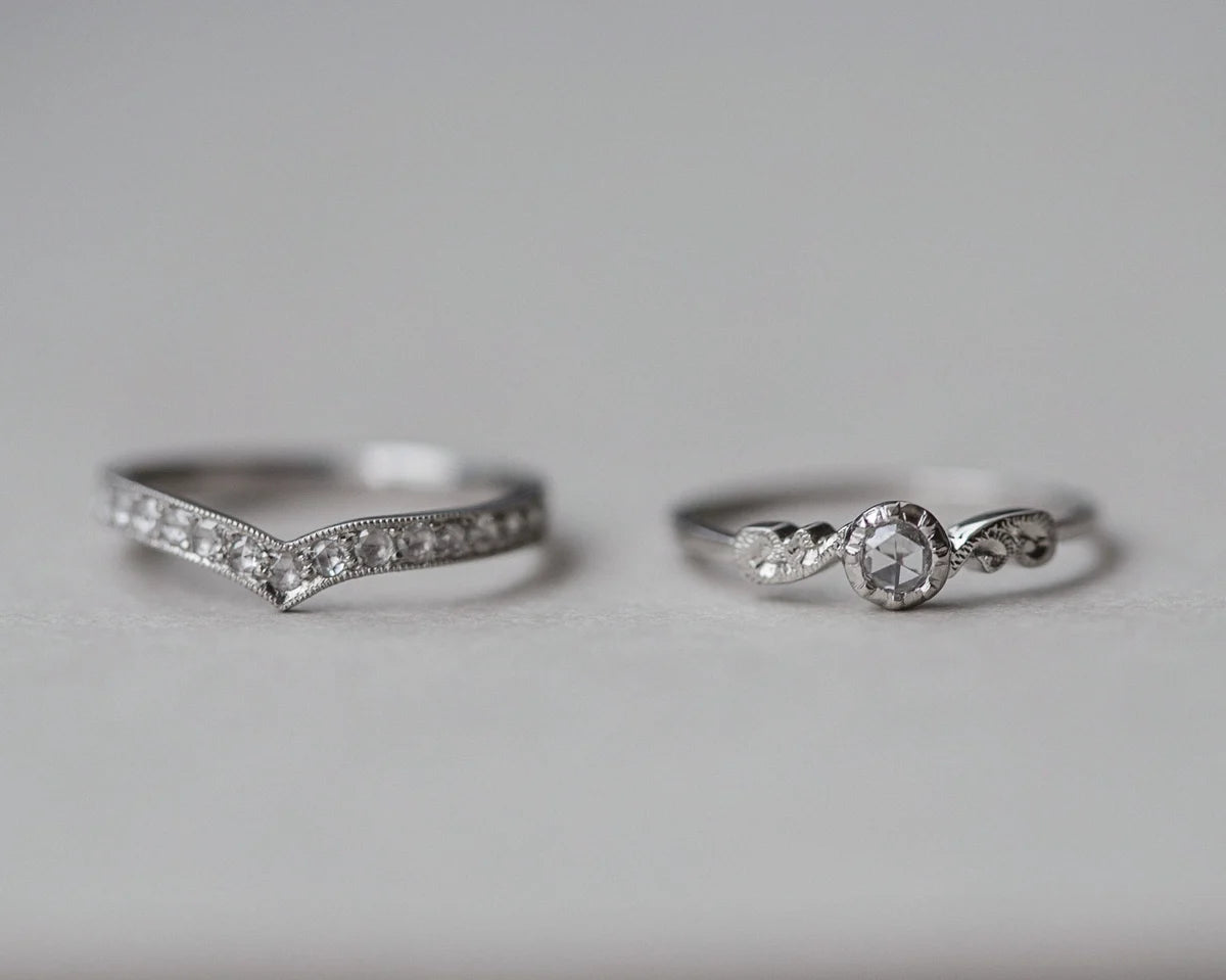 Two silver rings with diamond accents on a light gray background
