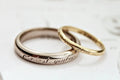 Two gold rings with engraved text on a light background