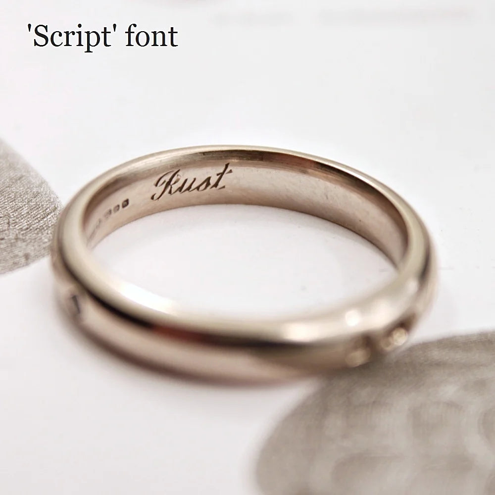 Rose gold ring with 'Just' engraved on a white surface